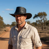 Man wearing a Jacaru 1150 Kangaroo Breeze Hat and light-colored shirt standing on a dirt road with trees in the background