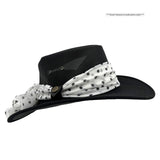 Black wide-brimmed hat with a white scarf with black polka dots on a white background
