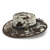 A Jacaru 1049 Rustler leather hat with a cowhide pattern and a braided leather band.
