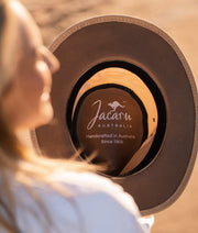 Person holding a Jacaru Australia hat with a blurred background