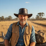 Man in outdoor setting wearing a cowboy hat and brown vest.
