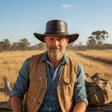 Man in outdoor setting wearing a cowboy hat and brown vest.