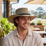 Man wearing a beige hat and light shirt outdoors with blurred background