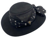 Black wide-brimmed hat with a polka dot print scarf on a white background