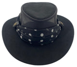 Black wide-brimmed hat with a polka dot print scarf on a white background
