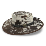 A Jacaru 1049 Rustler leather hat with a cowhide pattern and a braided leather band.