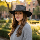Woman wearing a black hat and gray sweater outdoors with blurred background