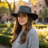 Woman wearing a black hat and gray sweater outdoors with blurred background