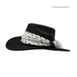 Black hat with a white polka dot scarf on a white background