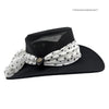 Black hat with a white polka dot scarf on a white background