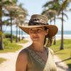 Woman wearing a Horizon Hat with Scarf leopard print band on a beach path with palm trees.