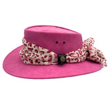 A Fuchsia Jacaru 1103 Alice hat made from vegan leather, featuring a wide brim and a multicolored scarf adorned around the base.
