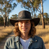 Person wearing a Roo Crushy Hat in a natural setting with trees and open space.