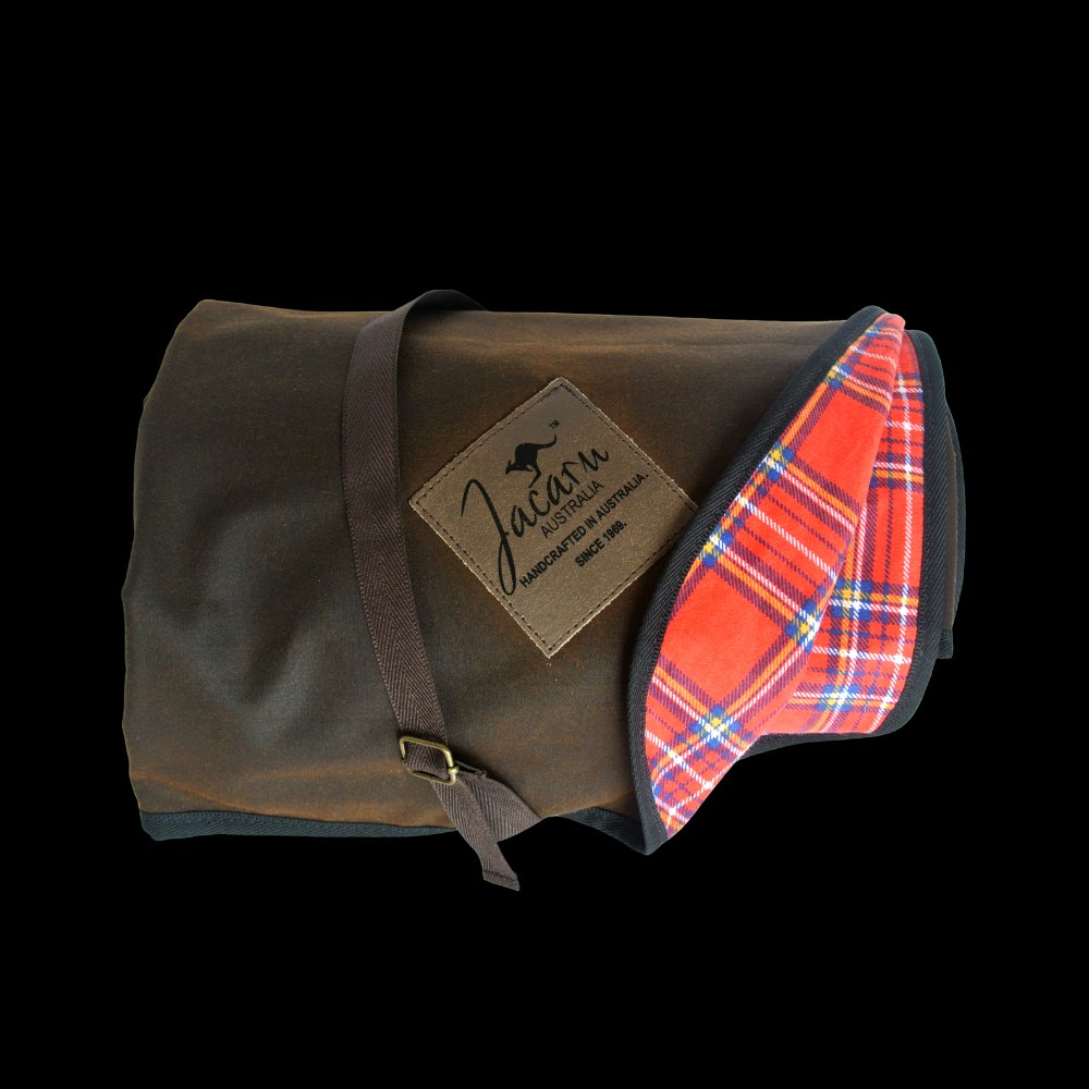 Jacaru 8003 brown oilskin picnic blanket rolled with strap showing red tartan cotton lining and branded leather patch.