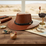 Jacaru Auburn Brown Ostrich Hat on a rustic desk with travel decor.