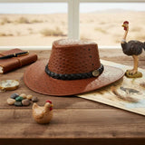 Jacaru Auburn Brown Ostrich Hat on a rustic desk with travel decor.