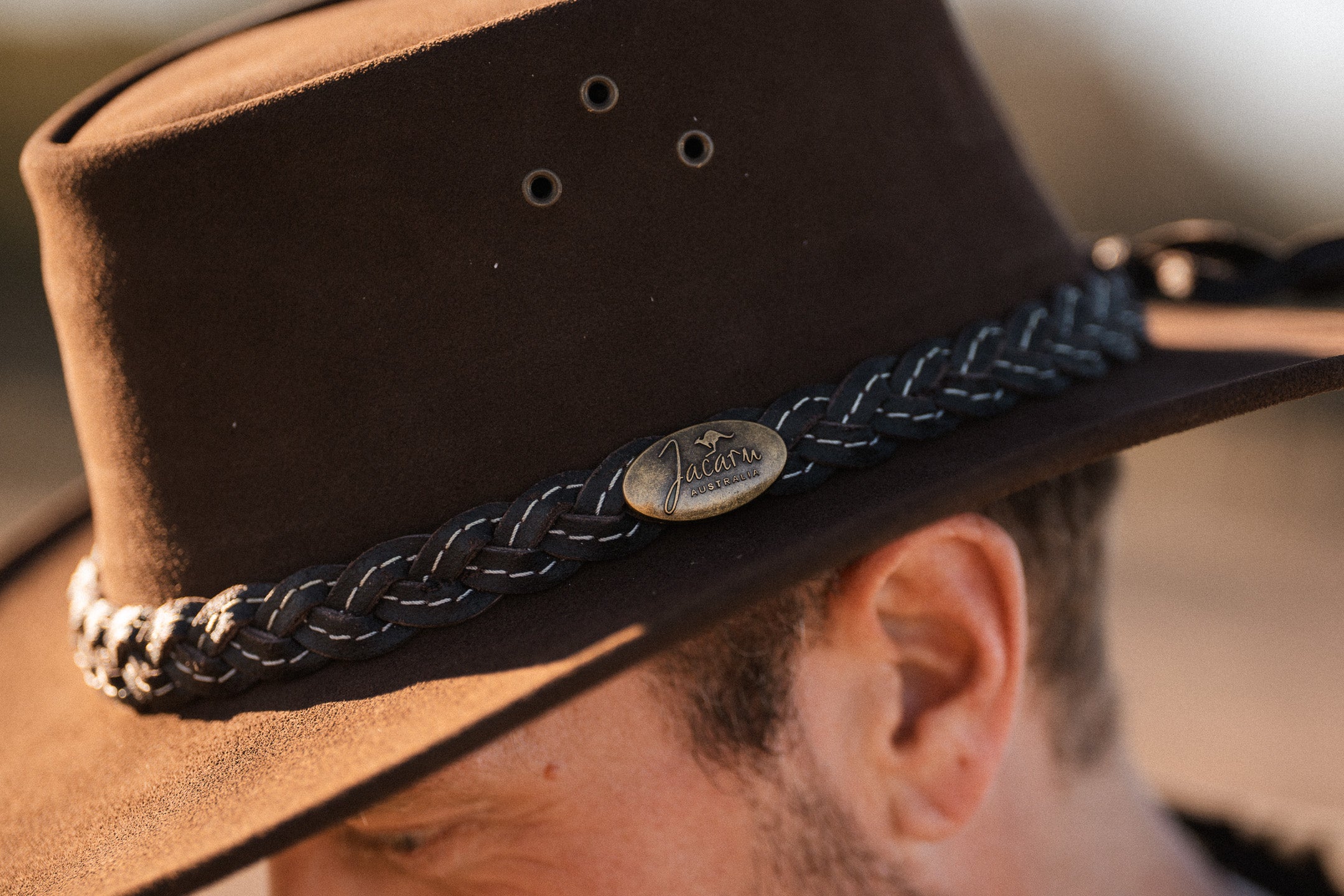 Brown hat with braided band and logo close-up jacaru