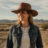 Smiling woman in an Jacaru Auburn Brown Ostrich Hat and denim jacket.